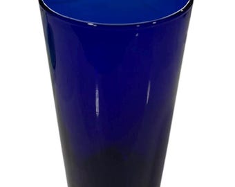 Può includere: Un bicchiere alto e cilindrico di un blu intenso e vibrante. Il bicchiere ha una superficie liscia e lucida e una forma leggermente affusolata, con una tonalità di blu più scura verso la base. Il bicchiere è vuoto.