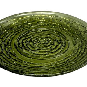 Puede incluir: Un plato de vidrio verde con un diseño texturizado en espiral. El plato es redondo y tiene un borde ligeramente elevado.
