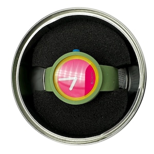 Pu&ograve; includere: Un orologio da polso verde e giallo con un quadrante rosa e lancette bianche. L'orologio &egrave; in una scatola rotonda d'argento con imbottitura in schiuma nera.