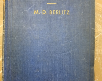 May include: A blue hardcover book with the title "LIBRO ESPAÑOL" and the author "M.D. BERLITZ" printed in gold lettering.
