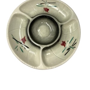 May include: A vintage serving dish with a central dip bowl. The off-white ceramic dish has three sections and is decorated with red, black, and green floral accents. The dish is round and has a leaf-like design.