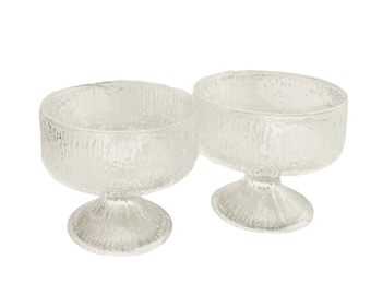 May include: Two clear glass dessert bowls featuring a textured, bark-like exterior finish. Each bowl has a wide, circular opening, a deep basin, and a short, sturdy pedestal base with a matching textured surface on the exterior of the stem.