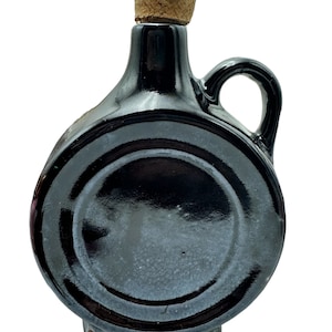 May include: A black ceramic bottle with a cork stopper. The bottle has a round body and a handle.