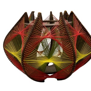 May include: A geometric string art sculpture with a brown wooden frame and red, yellow, and green string. The sculpture is shaped like a sphere and has a complex pattern of intersecting lines.