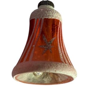 May include: A vintage Christmas bell ornament. The bell is red with white vertical stripes and a star design. The top and bottom edges are dusted with white glitter. A black metal loop is at the top for hanging.