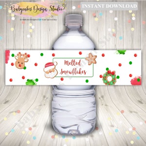 May include: Water bottle label with a white background and red and green watercolor splatters. The label features gingerbread cookies, including a reindeer, Santa, a star, and a wreath. The text on the label reads "Melted Snowflakes".