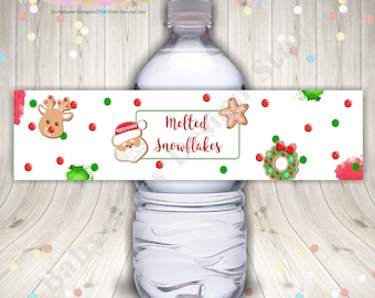 May include: Water bottle label with a white background and red and green watercolor splatters. The label features gingerbread cookies, including a reindeer, Santa, a star, and a wreath. The text on the label reads "Melted Snowflakes".