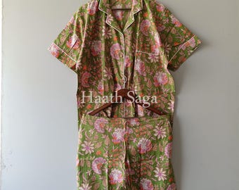Op de afbeelding: Groene pyjamaset met bloemenprint. De set bevat een overhemd met korte mouwen en bijpassende shorts. De pyjama's hebben een witte bies en een bloemenpatroon in roze, oranje en groene tinten. De tekst "Haath Saga" is zichtbaar.