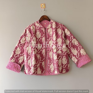 Könnte beinhalten: Gesteppte Jacke in Staubrosa mit sich wiederholendem beigefarbenem Tiermuster. Die Jacke hat zwei Vordertaschen und gestreifte Manschetten. Innen und am Saum ist sie ebenfalls gestreift. Der Text "Jaath saga" ist sichtbar.