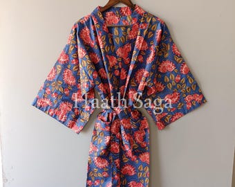 May include: A blue floral print robe with red flowers and yellow accents. The robe has wide sleeves and a matching belt. The text "Haath Saga" is visible on the robe. The robe is hanging on a wooden hanger.