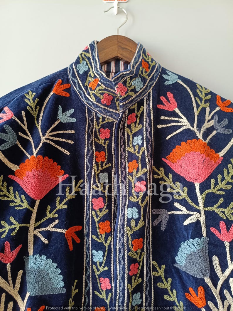 May include: A dark blue jacket with intricate floral embroidery in shades of pink, orange, and blue. The jacket features a high collar and a detailed pattern of flowers and leaves. The text "Haathi Saga" is visible on the jacket.