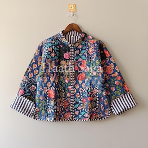 May include: A quilted jacket with a floral pattern in shades of blue, red, and pink. The jacket has a mandarin collar and striped cuffs. The text "Haath Saga" is visible on the front.