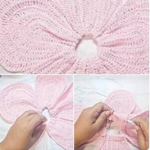 May include: Close-up and medium shots of a light pink crocheted flower. The flower has a circular center and petal-like sections. Hands are shown manipulating the crochet work, with a needle and thread visible.