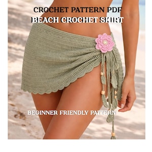 May include: A sage green crochet beach skirt with a scalloped edge and a pink flower accent. The skirt has fringe with wooden beads and the text "CROCHET PATTERN PDF BEACH CROCHET SKIRT BEGINNER FRIENDLY PATTERN".