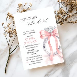 May include: A bridal shower invitation with the text "She's Tying the Knot." The invitation features a watercolor illustration of a diamond ring with a pink ribbon. Details include the bride's name, date, time, and location.