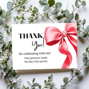 May include: A white card with the words "THANK You!" and a pink bow. The text "for celebrating with me! Your presence made the day truly special" is also on the card. Green leaves surround the card.