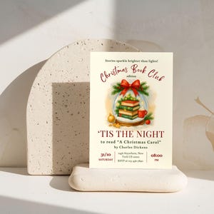 Może przedstawiać: Kremowe zaproszenie na wydanie Christmas Book Club, z akwarelową ilustracją książek w kuli śnieżnej, czerwoną kokardą i tekstem "'Tis the Night to read 'A Christmas Carol'" autorstwa Charlesa Dickensa.