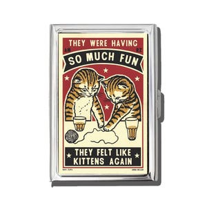 Könnte beinhalten: Eine silberne Zigarettenetui mit einer Illustration im Vintage-Stil von zwei Kätzchen mit braunen und schwarzen Streifen. Das Bild enthält den Text "THEY WERE HAVING SO MUCH FUN" und "THEY FELT LIKE KITTENS AGAIN" in einem rot-schwarzen Design.