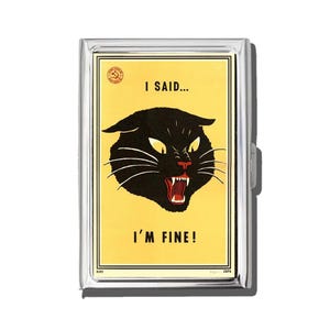 May include: A silver metal cigarette case with a yellow background featuring a black cat illustration with the text "I SAID... I'M FINE!". The cat has white whiskers, yellow eyes, and red teeth.