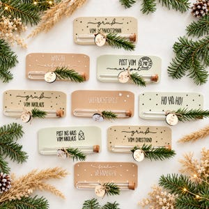 Könnte beinhalten: Eine Sammlung von neun rechteckigen Holzschildern in Beige und Salbeigrün, jedes mit einem klaren Glasreagenzglas mit Korkstopfen, einem kleinen Tannenzweig und einem runden Holzanhänger mit dem deutschen Text Für dich versehen.