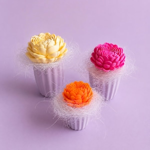 May include: Three decorative flower arrangements. A yellow, orange, and pink flower sits in a small, white, ribbed vase. The flowers are surrounded by white filler, set against a purple background.