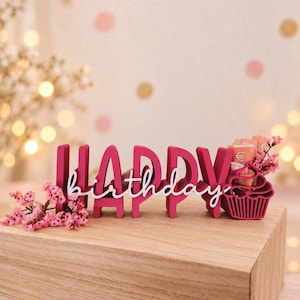 Könnte beinhalten: Ein dunkelrosa Holzschild mit dem Wort HAPPY in Blockbuchstaben und dem Wort birthday in weißer Schreibschrift. Ein dunkelrosa Cupcake-Halter auf der rechten Seite enthält gerollte Euro-Banknoten, verziert mit kleinen rosa Blüten.