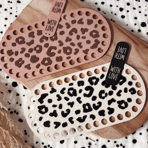 May include: Two oval-shaped bases with perforated edges for crafting. One base is light pink with a dark brown leopard print, and the other is cream with a black leopard print. Each base features a vertical tag labeled WITH LOVE.
