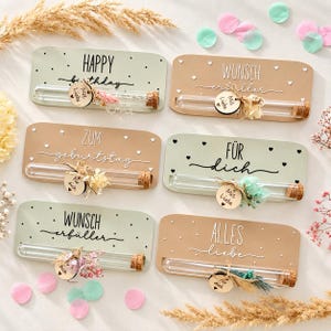Könnte beinhalten: Sechs rechteckige Schilder in Salbeigrün und Beige mit Glasreagenzgläsern und Korkstopfen. Jedes Schild trägt Aufschriften wie Happy Birthday, Wunsch Erfüller, Zum Geburtstag, Für Dich und Alles Liebe, verziert mit Trockenblumen und kleinen Holzanhängern.