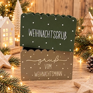 Könnte beinhalten: Zwei rechteckige Aufbewahrungsboxen aus Holz mit gewelltem oberen Rand. Die obere Box ist dunkelgrün mit weißen Sternen und dem Text WEIHNACHTSGRUB. Die untere Box ist hellbraun mit weißen Sternen und dem Text GRUB VOM WEIHNACHTSMANN in weißer Schrift.