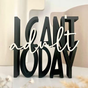 Könnte beinhalten: Schwarz-weißes Dekoschild mit dem Schriftzug "I can't adult today". Die Wörter sind in einem 3D-Design gehalten, wobei das Wort "adult" in einer Schreibschrift dargestellt ist. Das Schild ist ein lustiges Wohnaccessoire.