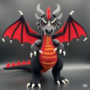 Può includere: Un drago all'uncinetto fatto a mano in nero, rosso e grigio. Il drago ha grandi ali con dettagli rossi e neri, occhi arancioni e artigli bianchi. Il petto del drago è a righe rosse e arancioni. Il drago è su una superficie scura.