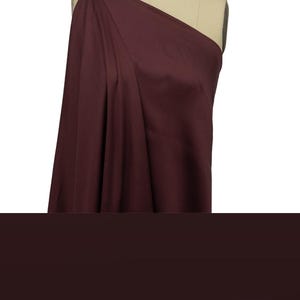 May include: A deep burgundy fabric swatch draped over a dress form. The fabric has a smooth, silky texture.