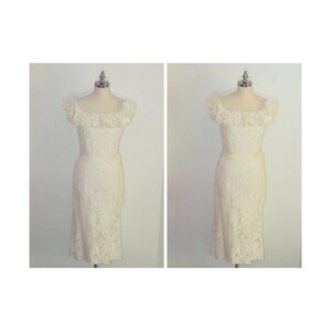Puede incluir: Un vestido blanco de encaje con un escote de volantes y una cinta en la cintura. El vestido est&aacute; en un maniqu&iacute;.