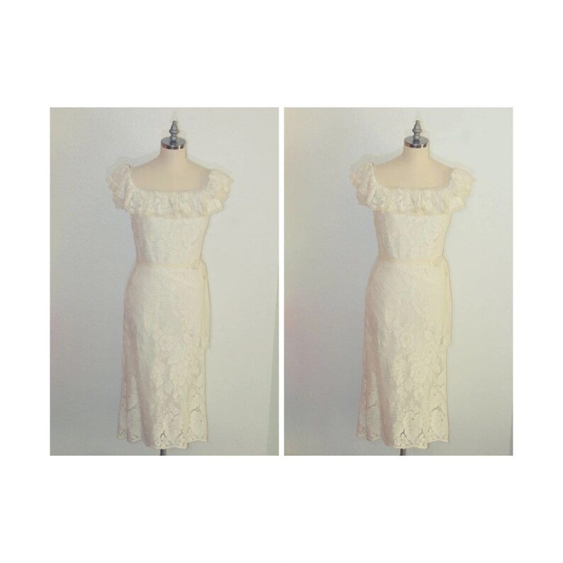 Puede incluir: Un vestido blanco de encaje con un escote de volantes y una cinta en la cintura. El vestido est&aacute; en un maniqu&iacute;.