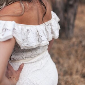 Puede incluir: Un vestido blanco de encaje de hombros descubiertos con un escote de volantes. El vestido es entallado y tiene una falda fluida.