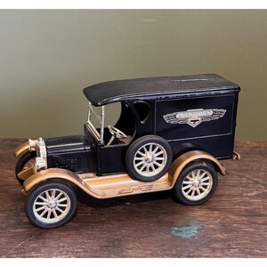 May include: A black and gold vintage-style toy truck with the text "ACME STORES" on the side. The truck has a black roof, gold accents, and spoked wheels. The words "LIMITED EDITION" are visible on the front.