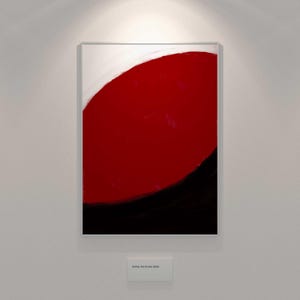 Puede incluir: Pintura abstracta con un gran círculo rojo, una base negra y una sección superior blanca. La obra está enmarcada y colgada en una pared blanca, creando un fuerte contraste.