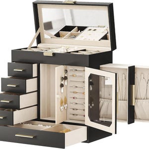 May include: A black jewelry box with multiple drawers and compartments. The box has a mirrored lid and gold-colored hardware. The interior is lined with a light-colored fabric, and the drawers are various sizes for different jewelry items.