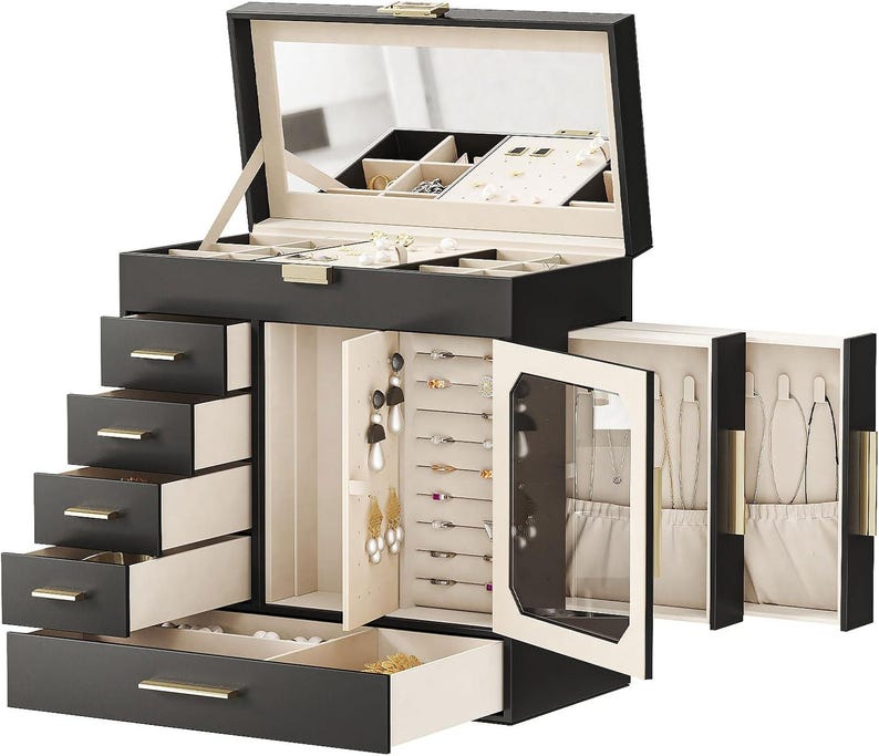May include: A black jewelry box with multiple drawers and compartments. The box has a mirrored lid and gold-colored hardware. The interior is lined with a light-colored fabric, and the drawers are various sizes for different jewelry items.