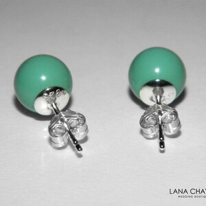 May include: A pair of silver stud earrings with turquoise round beads. The earrings have a post and butterfly back.