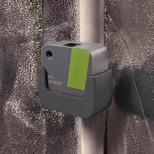 Könnte beinhalten: Ein graues, quadratisches HT.w SENSOR-Gerät, das an einer vertikalen Stange befestigt ist. Der Sensor verfügt über eine kleine kreisförmige Öffnung oben links und einen rechteckigen, limettengrünen Aufkleber auf der rechten Seite. Er wird von einer dunkelgrauen Kunststoffhalterung gehalten.