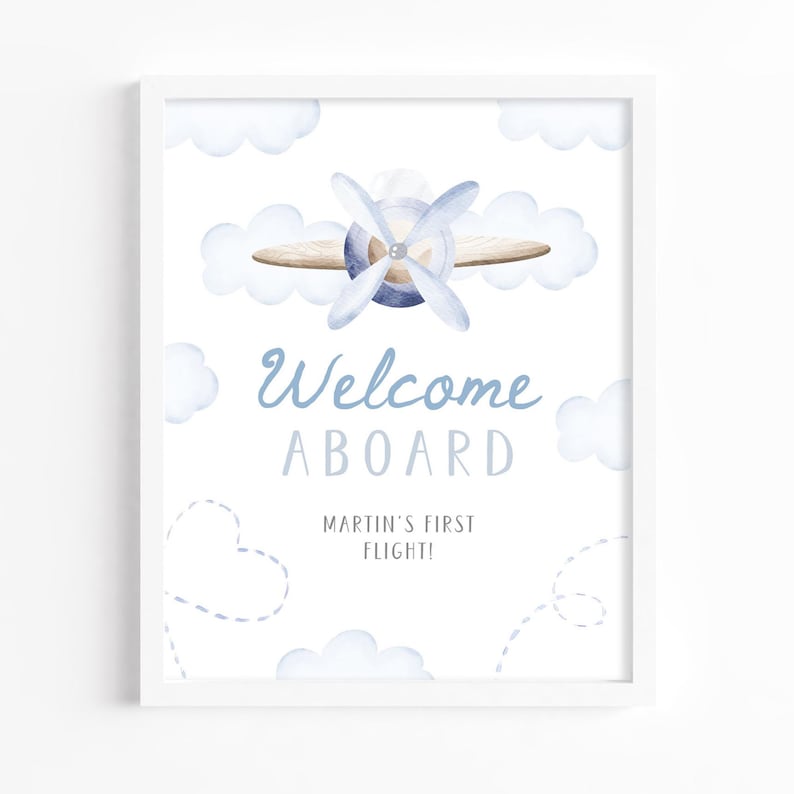 May include: A framed print featuring a watercolor illustration of a biplane with a blue propeller and clouds. The text "Welcome Aboard" and "Martin's First Flight!" are written in blue script.