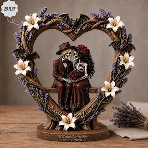 May include: A heart-shaped sculpture featuring two skeletons in formal attire sitting on a bench. The frame is decorated with white lilies, purple lavender, and small bats. The names Sarah and David are engraved, with Till Death Do Us Part 02/08/2026.