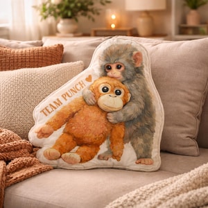 May include: A decorative pillow featuring two cartoon monkeys hugging. The pillow has a white background with the words "TEAM PUNCH" and a heart. The monkeys are in shades of orange and gray, with detailed facial features.