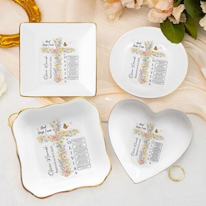 Puede incluir: Cuatro platos de cerámica blanca para baratijas en varias formas: cuadrada, redonda, festoneada y en forma de corazón. Cada plato tiene un borde dorado y presenta un diseño de cruz floral con texto "Dios dice que soy" y una fecha.