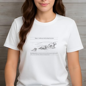 May include: White t-shirt featuring a black and white illustration of the evolution of a land-sea animal. The graphic includes the text "Figure 1. Staffyzozoic land-sealopod ancestors" and additional descriptive text below the illustration.