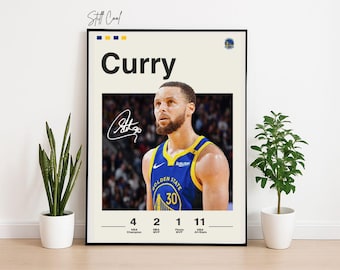 May include: A framed poster featuring basketball player Stephen Curry. The poster has a cream-colored background with the name "Curry" in bold black letters. Below the name is a photo of Curry in his Golden State Warriors jersey, with his signature. The poster includes his stats.
