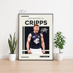 以下が含まれることがあります： 大きな白い文字で「CRIPPS」と書かれた、ネイビーブルーのジャージを着たフットボール選手の写真が特徴の額入りポスター。ポスターには「Carlton Blues Football Club」というテキストとサインが含まれています。ポスターは白い壁に表示されています。