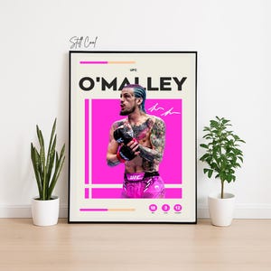 May include: A framed poster featuring UFC fighter O'Malley. The poster has a black border and a cream-colored background with a large pink rectangle. The fighter is shown with tattoos, blue hair, and wearing pink shorts and gloves. The poster includes the text "Still Cool".