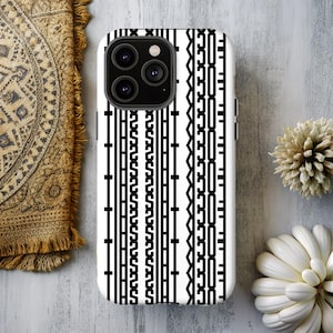 May include: White phone case with a black geometric pattern. The case features a series of vertical lines and shapes, creating a bold, graphic design. The phone case is shown on a light-colored surface.